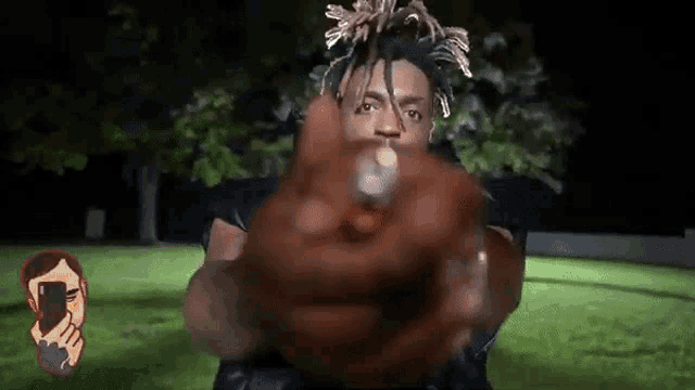 a man with dreadlocks is holding a gun in his hand in a park at night .
