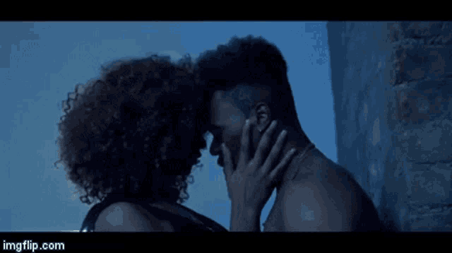 a man and woman are kissing in front of a brick wall ..