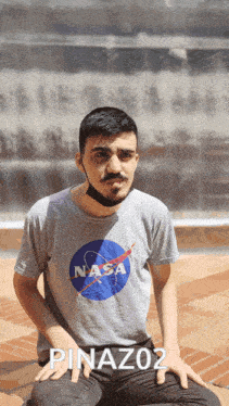 a man wearing a nasa t-shirt sits on the ground