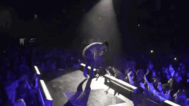 a man stands on a stage in front of a crowd while holding a microphone