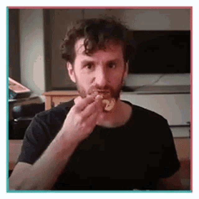 a man with a beard is eating a piece of pizza .