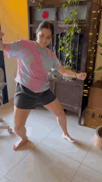 a woman in a tie dye shirt is dancing in a room .