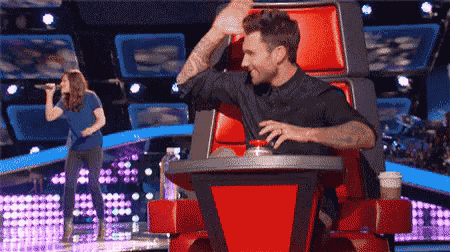 a man is sitting in a chair while a woman sings on a stage