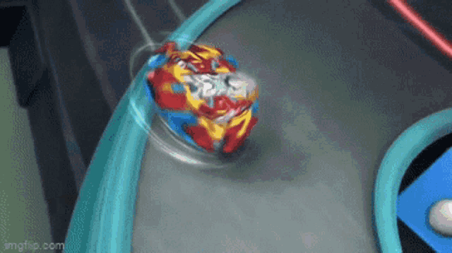 a red , yellow and blue spinning top is spinning on a track .