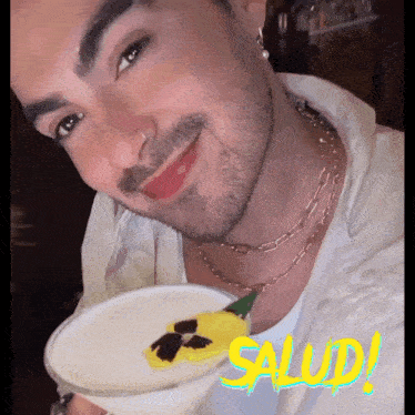 a close up of a man holding a plate with the word salud written in yellow