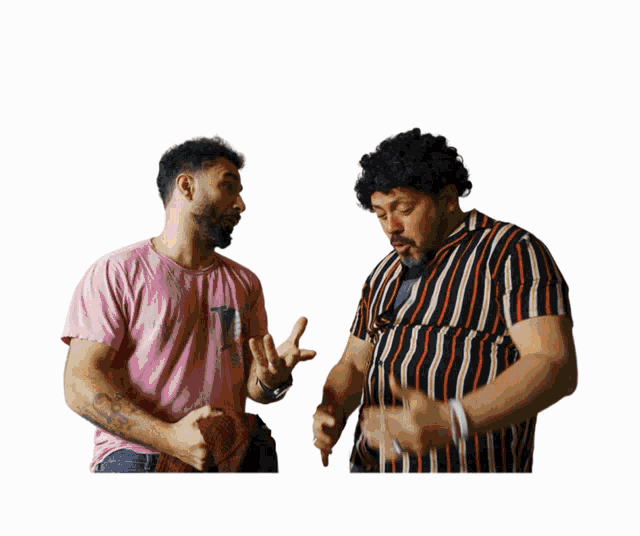 two men standing next to each other with one wearing a pink shirt