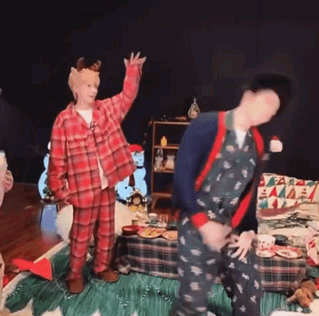 a man in a plaid shirt is standing next to another man in a christmas outfit .