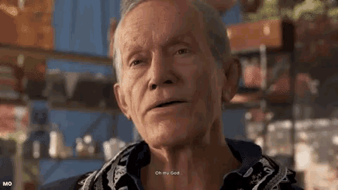 an elderly man is talking to another man in a video game while wearing a scarf around his neck .