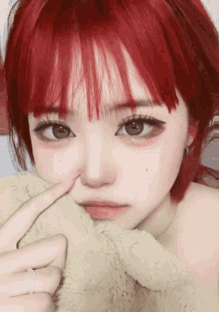 a girl with red hair is touching her nose