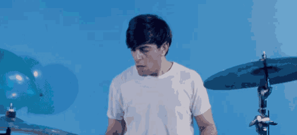 a man in a white shirt is playing drums
