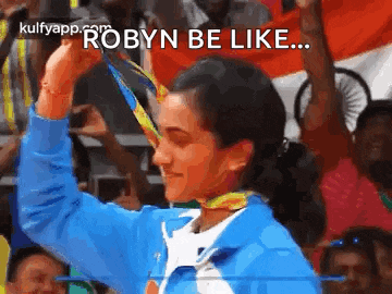 a woman in a blue jacket is holding a medal in her hand .