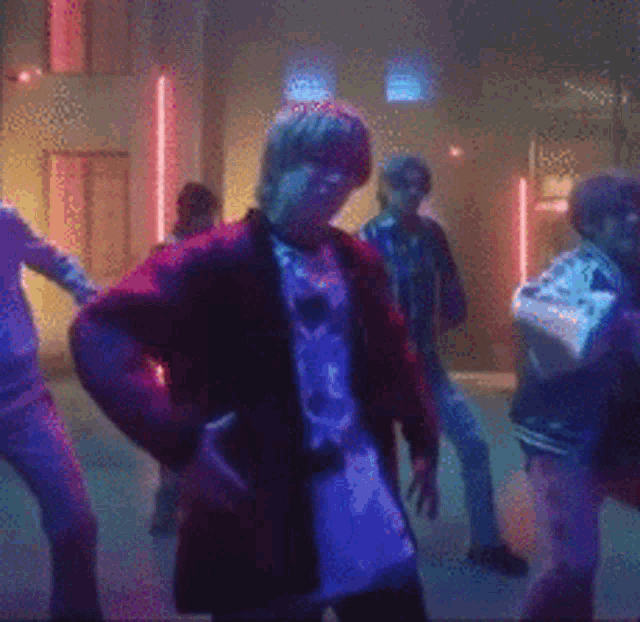 a group of people are dancing in a dark room with neon lights .