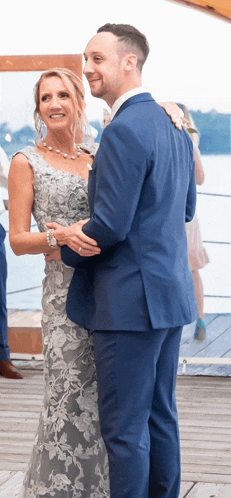 a man in a blue suit and a woman in a gray dress are dancing