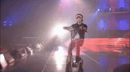a person is riding a scooter on a stage in a dark room .