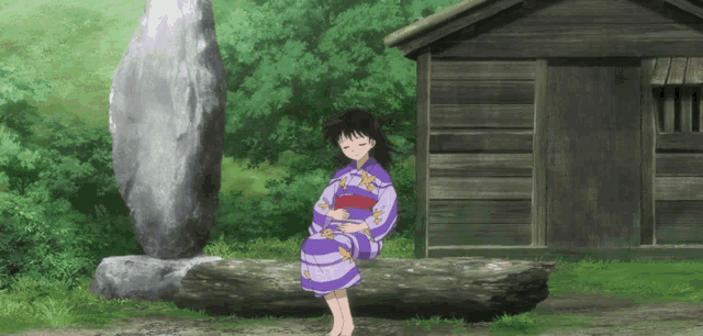 a girl in a kimono sits on a rock in front of a small wooden building