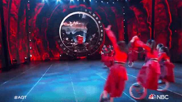 a group of people are performing on a stage with a nbc logo in the corner