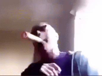 a man is smoking a cigar in front of a window in a room .
