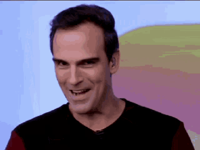 a man in a black shirt is smiling and making a face