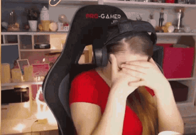 a woman wearing a virtual reality headset is sitting in a pro gamer chair covering her face .