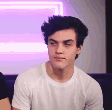 a young man is sitting on a couch wearing a white t-shirt .