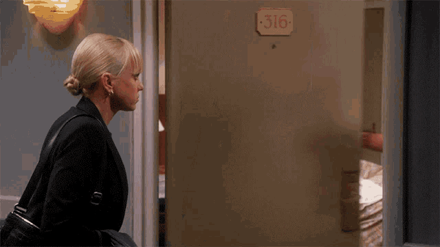 a woman standing in front of a door with the number 316 on it