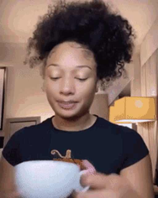 a woman in a black shirt is holding a cup of coffee .