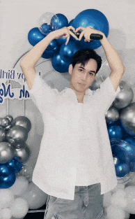 a man in a white shirt stands in front of balloons