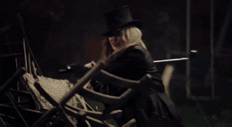 a woman wearing a top hat is holding a broken chair