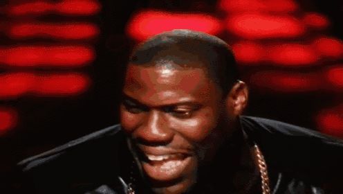 a man with his tongue hanging out is wearing a black jacket and gold chains .
