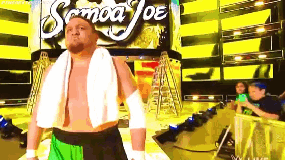 a shirtless wrestler with a towel around his neck stands in front of a sign that says samoa joe .