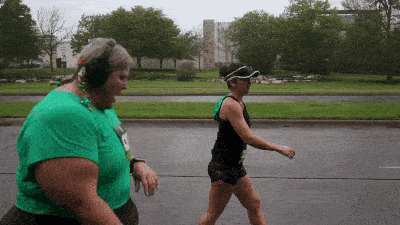 a woman wearing headphones walks next to another woman wearing a visor