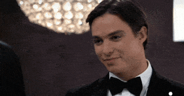 a man in a tuxedo with a bow tie looks at the camera