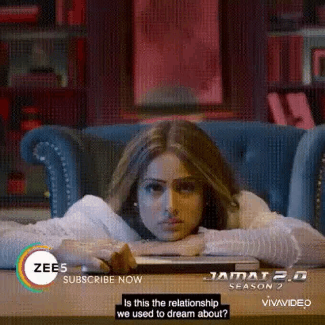 a woman is laying on a couch with her head resting on a laptop .