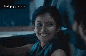 a woman is smiling while sitting in the back seat of a car with a man .