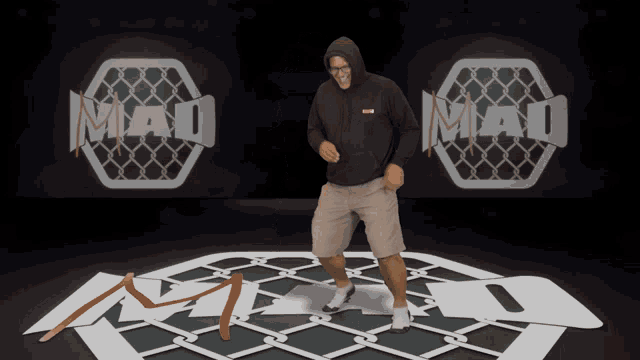a man in a hooded sweatshirt is dancing in front of the mad logo