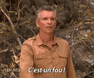 a man in a khaki shirt is standing in the woods and says c'est un fou !