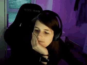 a woman wearing headphones is sitting in a chair with the word racer on the back