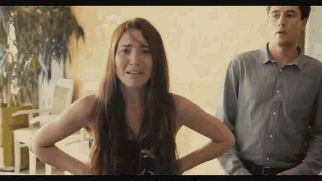 a woman with long red hair is standing next to a man in a grey shirt
