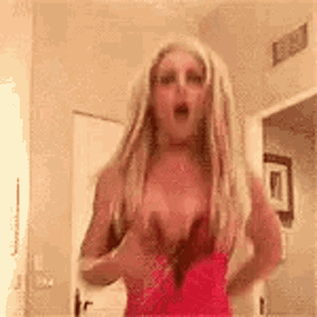 a woman in a red dress is standing in a room with her mouth open .