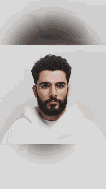 a man with glasses and a beard wearing a white hoodie