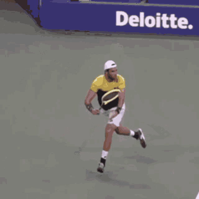 a man is running with a tennis racquet in front of a sign that says deloitte