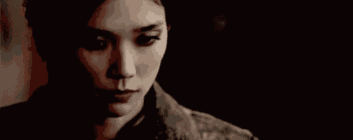 a close up of a woman 's face in a dark room with a serious look on her face .