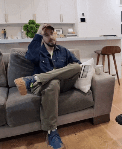 a man is sitting on a couch with his legs crossed and a pillow that says ' chicago ' on it