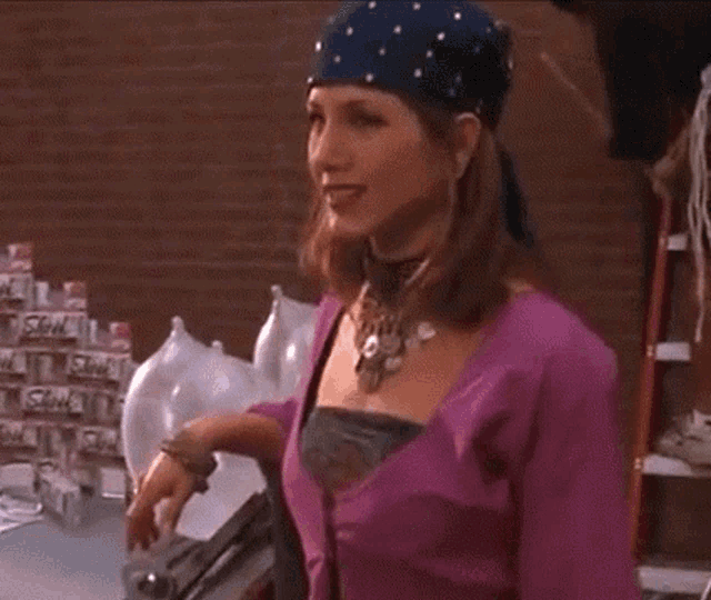 a woman wearing a purple shirt and a blue bandana is standing in front of a brick wall .