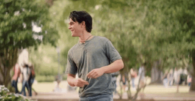 a man in a gray shirt is running in a park