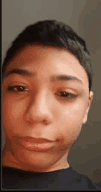 a close up of a young boy 's face with a black shirt on .