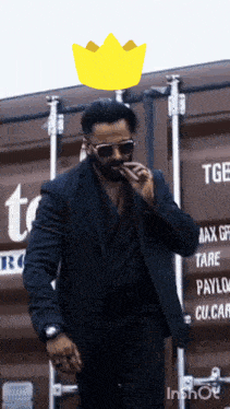 a man in a suit and sunglasses is standing in front of a container that says tge