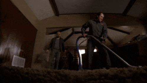two men are cleaning a carpet in a dark room