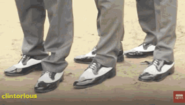 three men wearing black and white shoes are standing next to each other