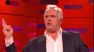 a man in a suit and white shirt is pointing up with his finger